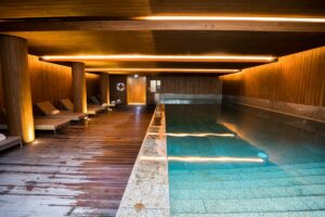 Indoor swimming pool with wooden walls and lounge chairs
