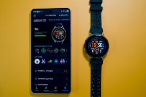 Smartwatch and smartphone displaying its app on a yellow background.
