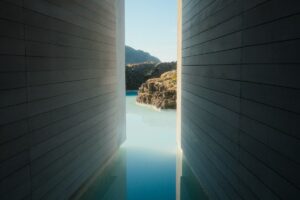 A view of milky blue water and rocky terrain through a narrow wooden corridor